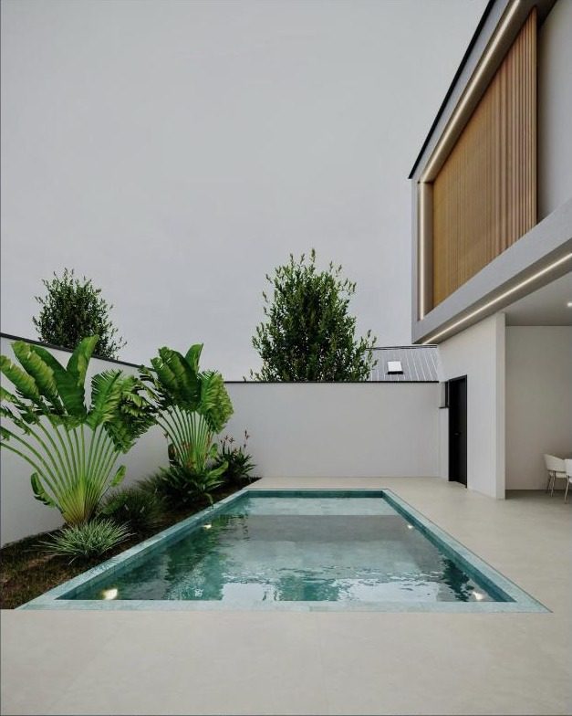 Área de lazer com piscina de borda reta e paisagismo tropical